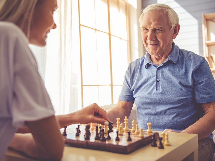 A woman and an old man playing chess