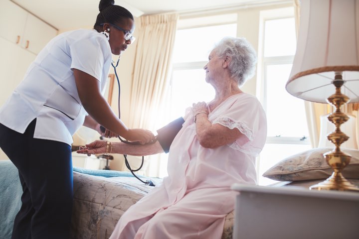 A nurse is checking the blood pressure of an older woman.