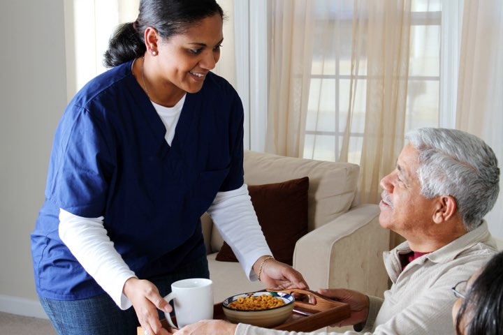 A nurse is serving food to an elderly person.