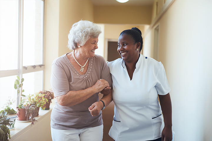 A nurse and an older woman smiling for the camera.