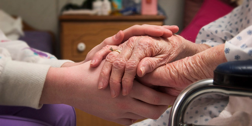 A person holding hands with an elderly woman.