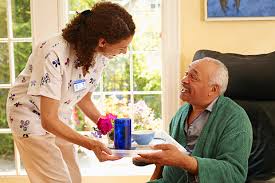 A nurse handing an elderly man some food.